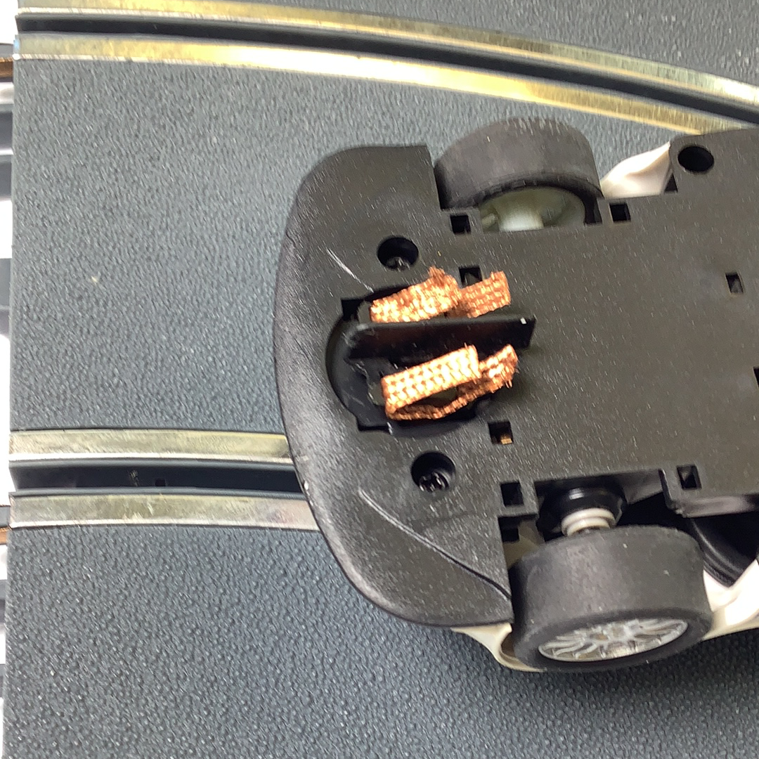 Small black plastic component with visible electrical contacts and wheel detail for SCX A10304X3U0