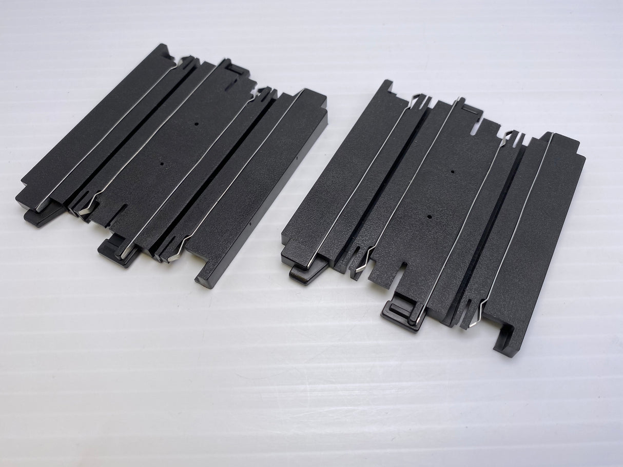 Two sets of black, straight model train tracks for assembly for Aurora Tomy AFX Vintage 70607