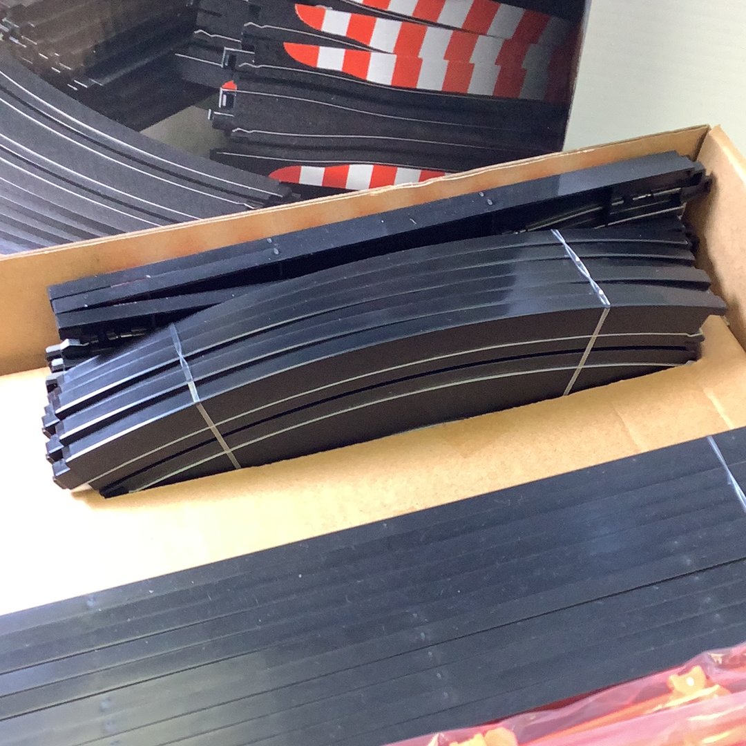Curved black track pieces stacked in an open box for AFX/Racemaster 21045