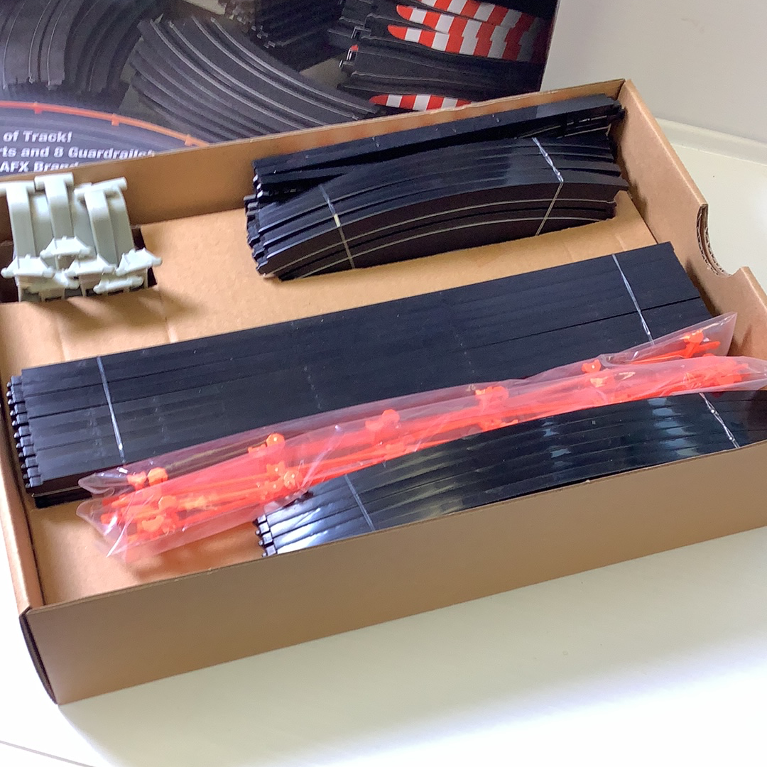 Assortment of model train track pieces and couplers in a box for AFX/Racemaster 21045