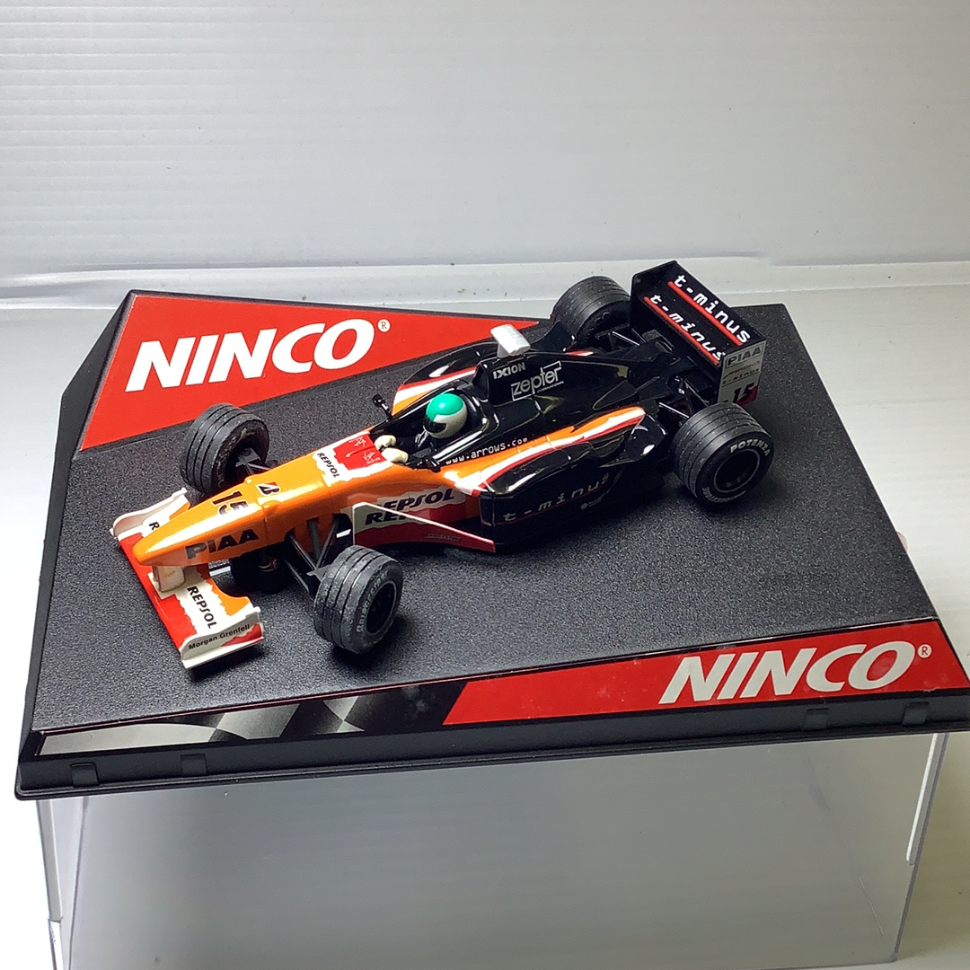 Slot car race car, orange and black, on a black display base for Ninco 50212