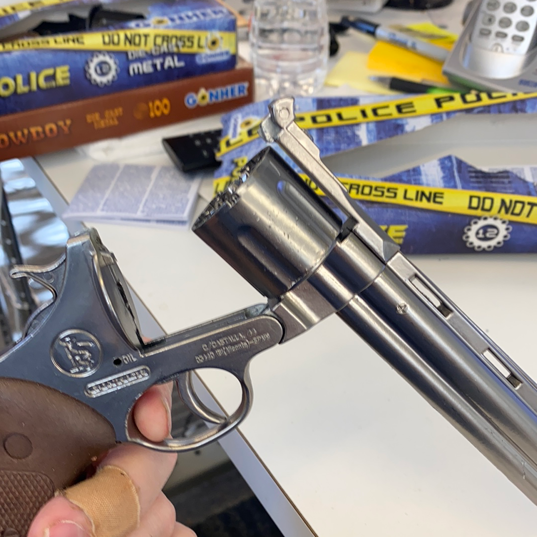 Silver toy revolver and pistol displayed on a surface with police tape for Gonher 123/0
