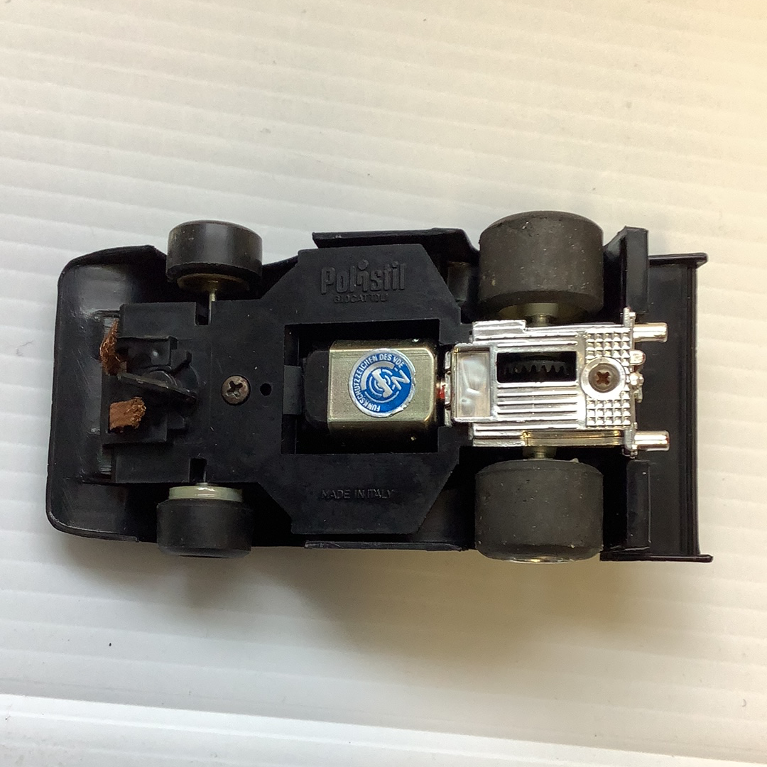Black slot car base showing internal components and wheels for REH Polistil A.108
