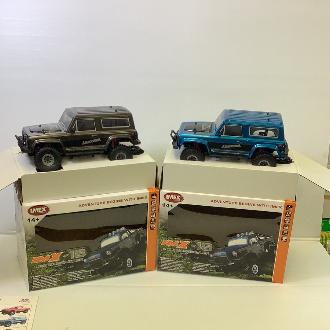 Two scale crawler vehicles displayed in open boxes for IMX IMX25005