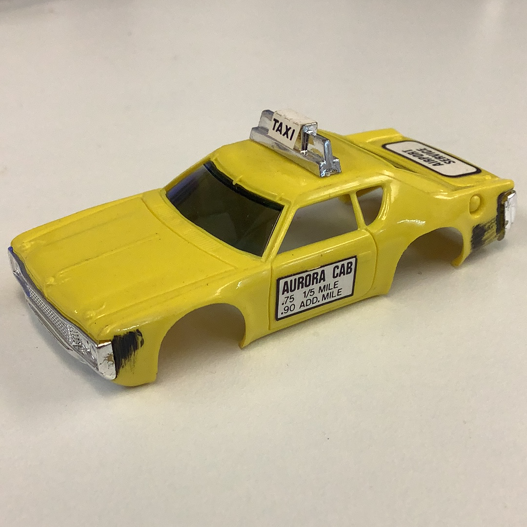 Yellow toy taxi cab with "Aurora Cab" signage on the side for Aurora / AFX / Tomy B1939Y