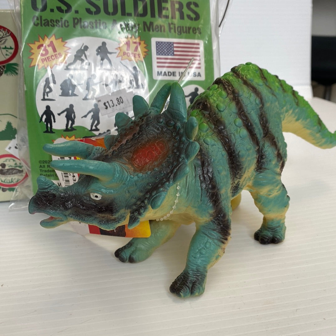 Green dinosaur toy figure next to a box of soldier action figures for Schylling
