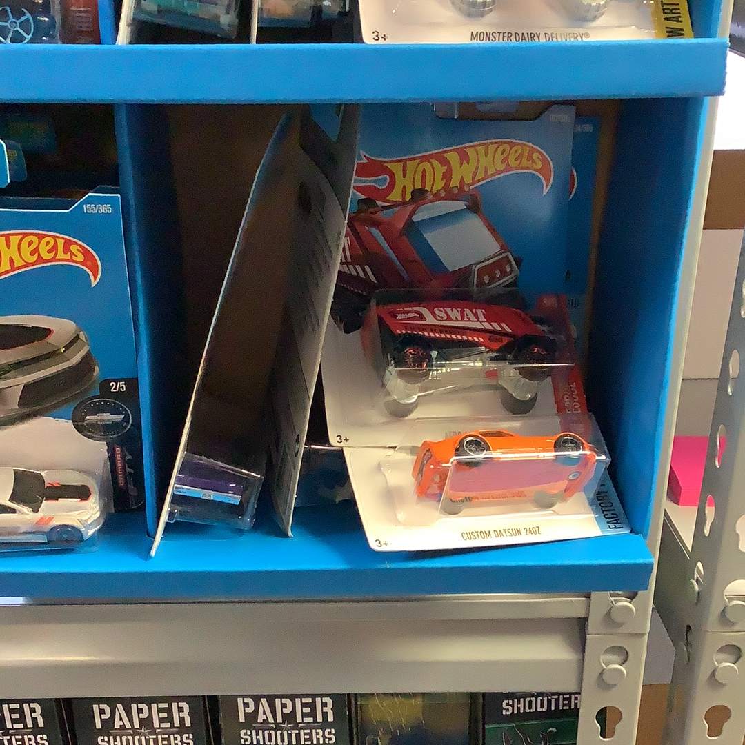 Assorted Hot Wheels cars displayed on blue shelving for UPD FDY58-K910 l Assorted, rear view