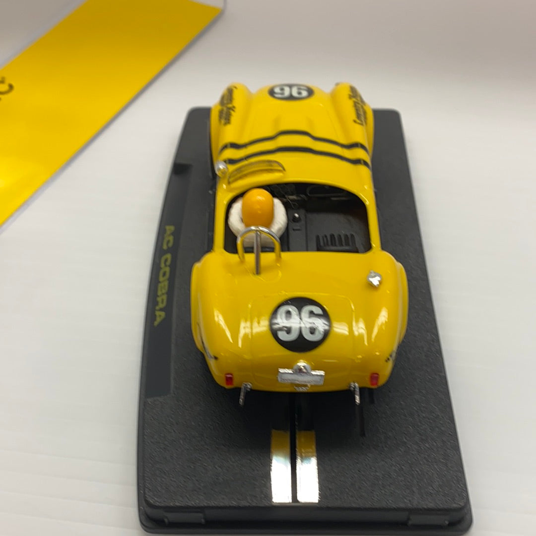 Yellow 1964 AC Cobra slot car on a black display base for REPROTEC RT/1964, rear view
