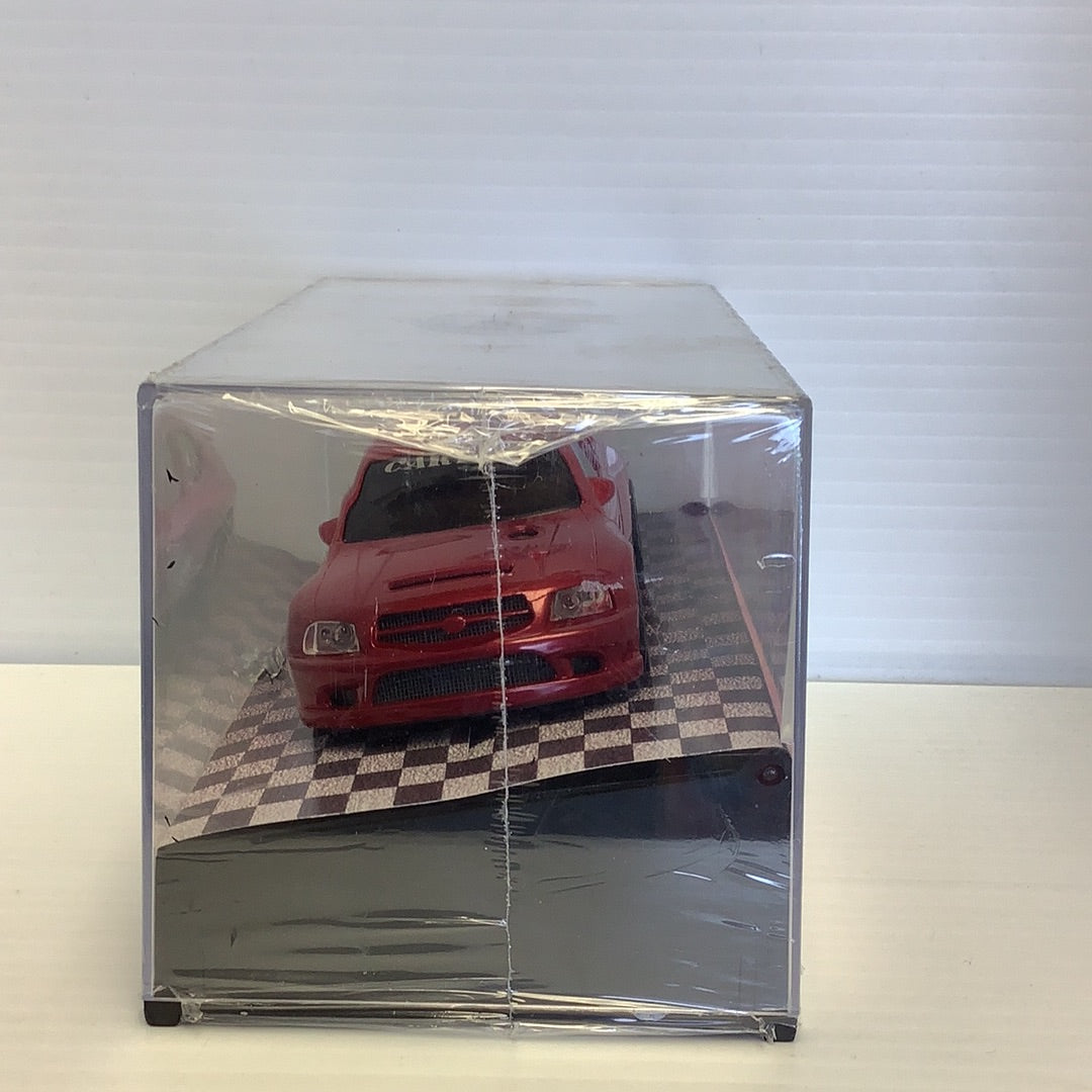 Red car model in clear acrylic display case on a checkered surface for CARTRIX 0312E