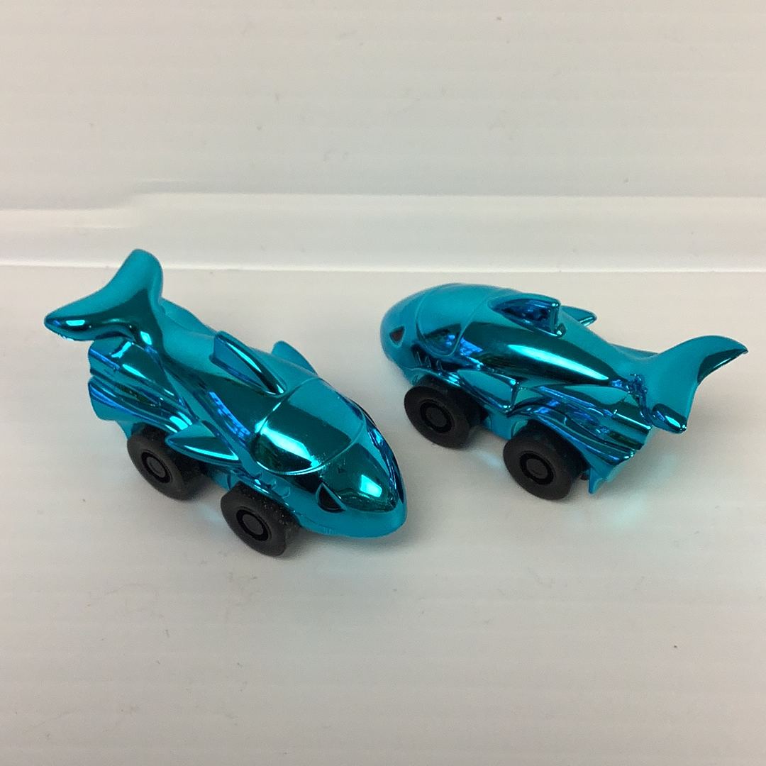 Two shiny, blue toy shark cars on a white surface for California Creations 20870, rear view