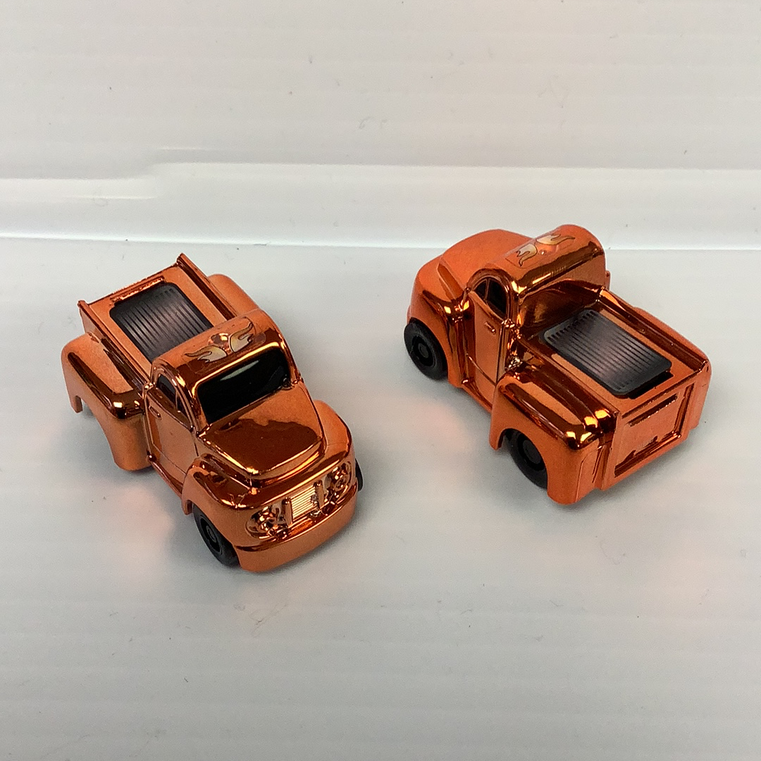 Two small, metallic orange toy trucks with visible internal details for California Creations 20553, rear view