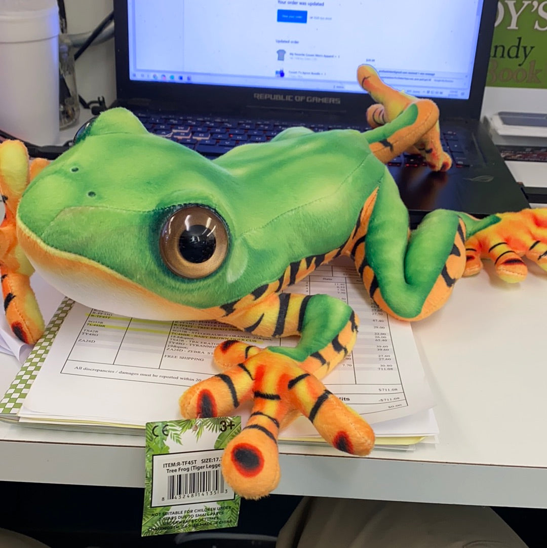 Green stuffed tree frog with orange tiger legs, resting on paperwork for Real Planet R-TF45T