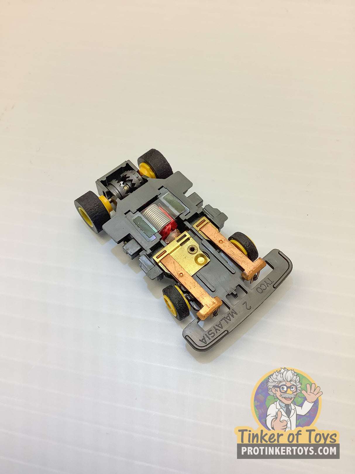 Black and yellow toy car chassis with wheels, showing mechanical details for Tyco TCR TCR1501
