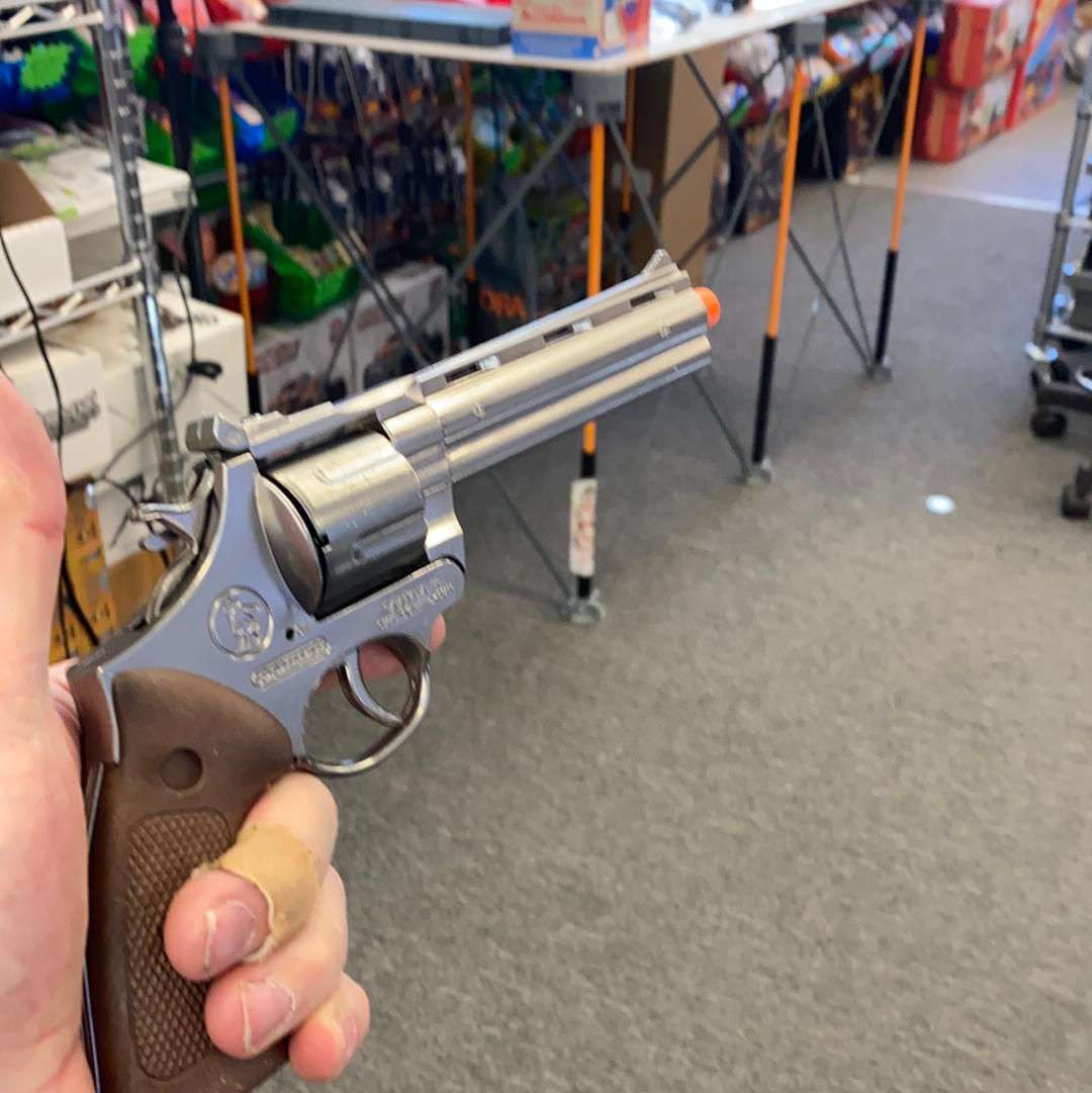 Silver toy revolver held in a hand against a retail background for Gonher 123/0