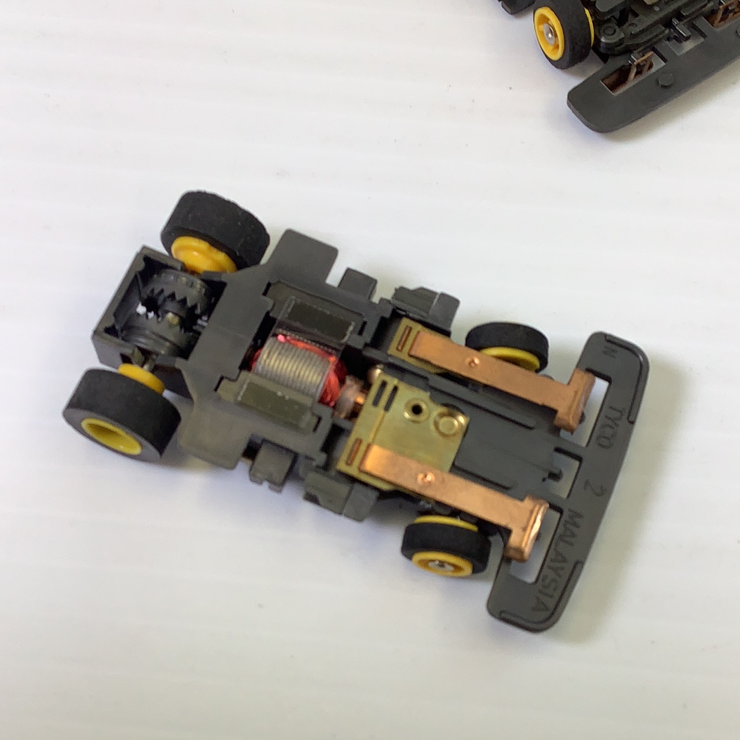 Black and gold toy car chassis with wheels, showing mechanical details for Tyco TCR TCR1501