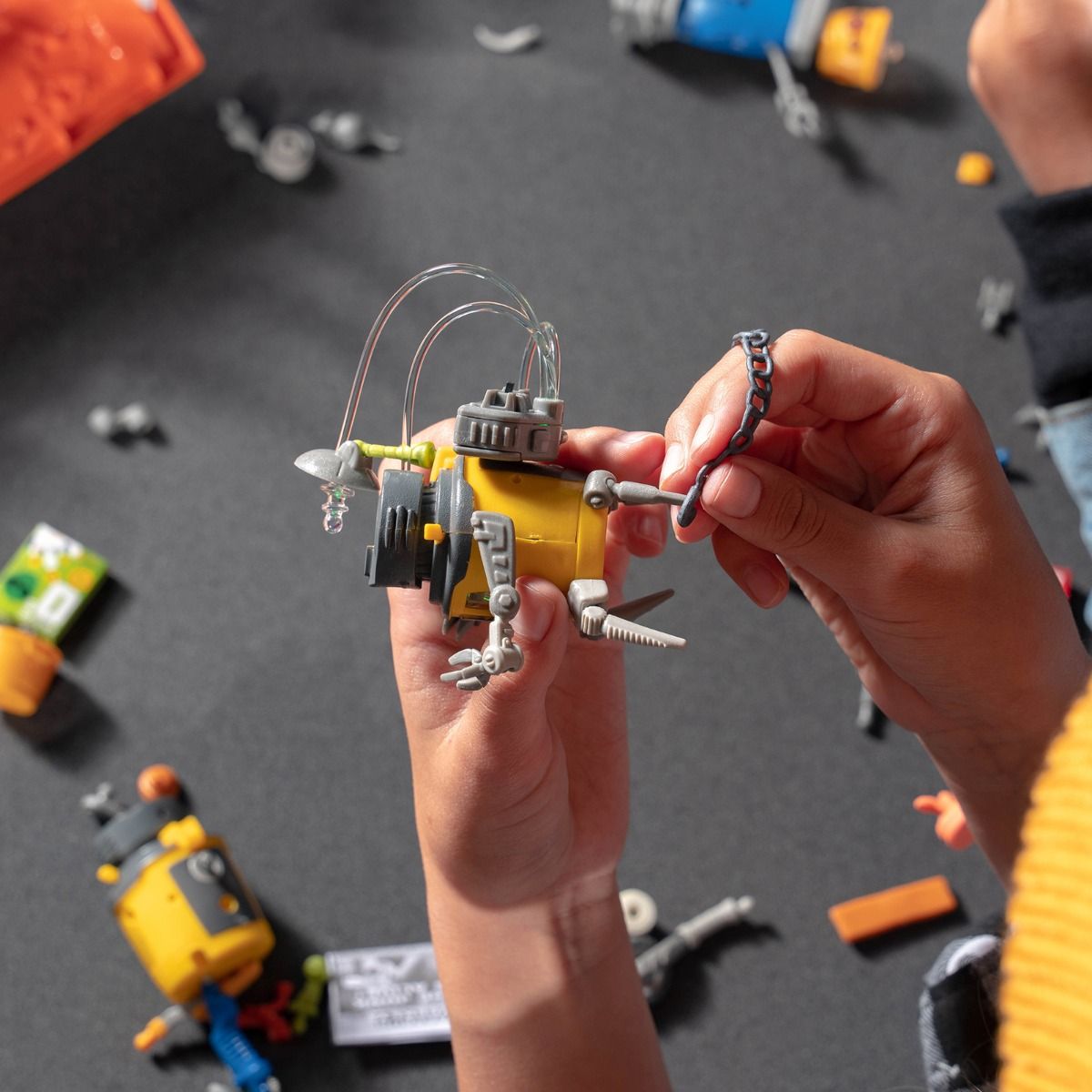 Child holds small, yellow robot toy with wires and mechanical parts for HexBug 430-6843
