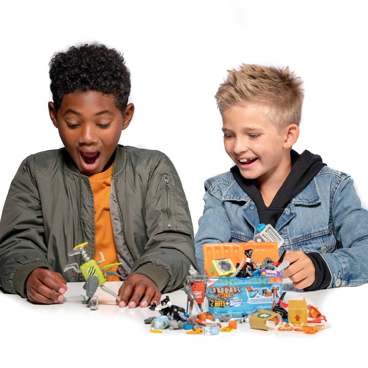 Two boys excitedly examine assorted junk toys and robot parts for HexBug 430-6842