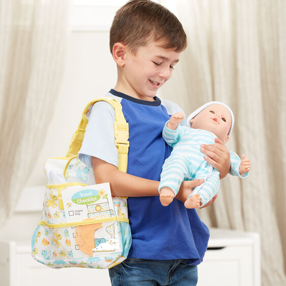 Boy holding doll with travel bag, ready for playtime adventure for Melissa and Doug 31707