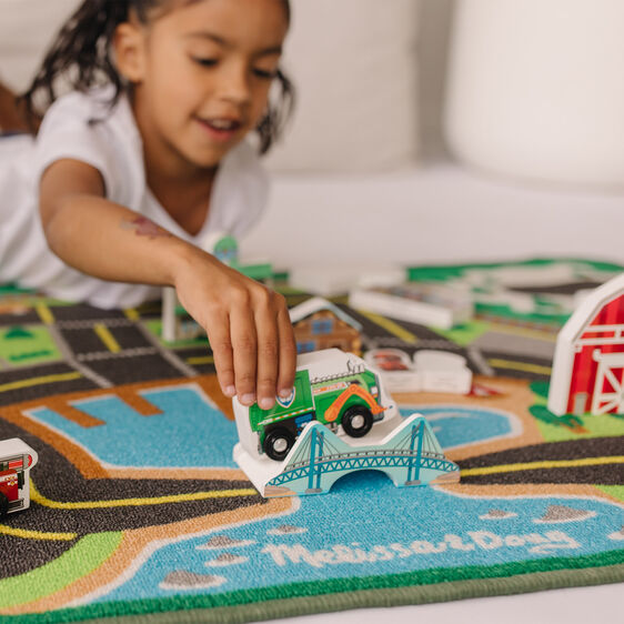 Child plays with toy vehicle on a Paw Patrol activity rug for Melissa and Doug 33273