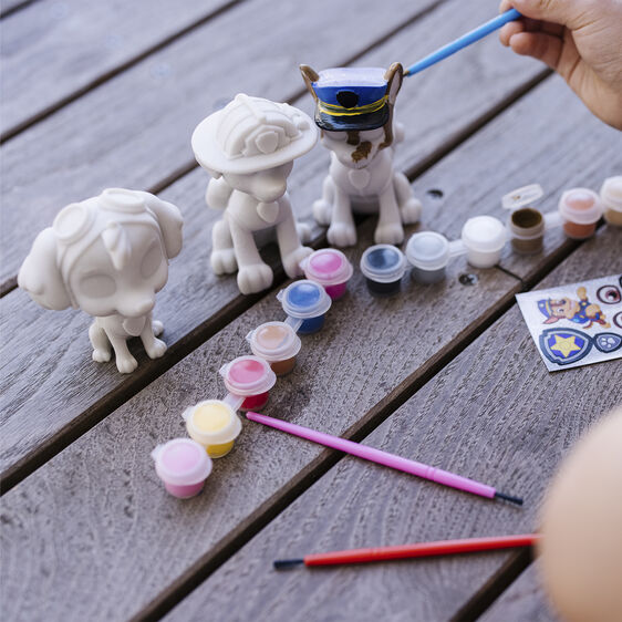 Craft kit with white pup figurines and small paint pots on a wooden surface for Melissa and Doug 33265