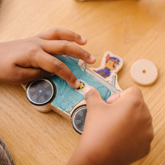 Child's hands assembling a wooden Paw Patrol vehicle craft kit for Melissa and Doug 33266