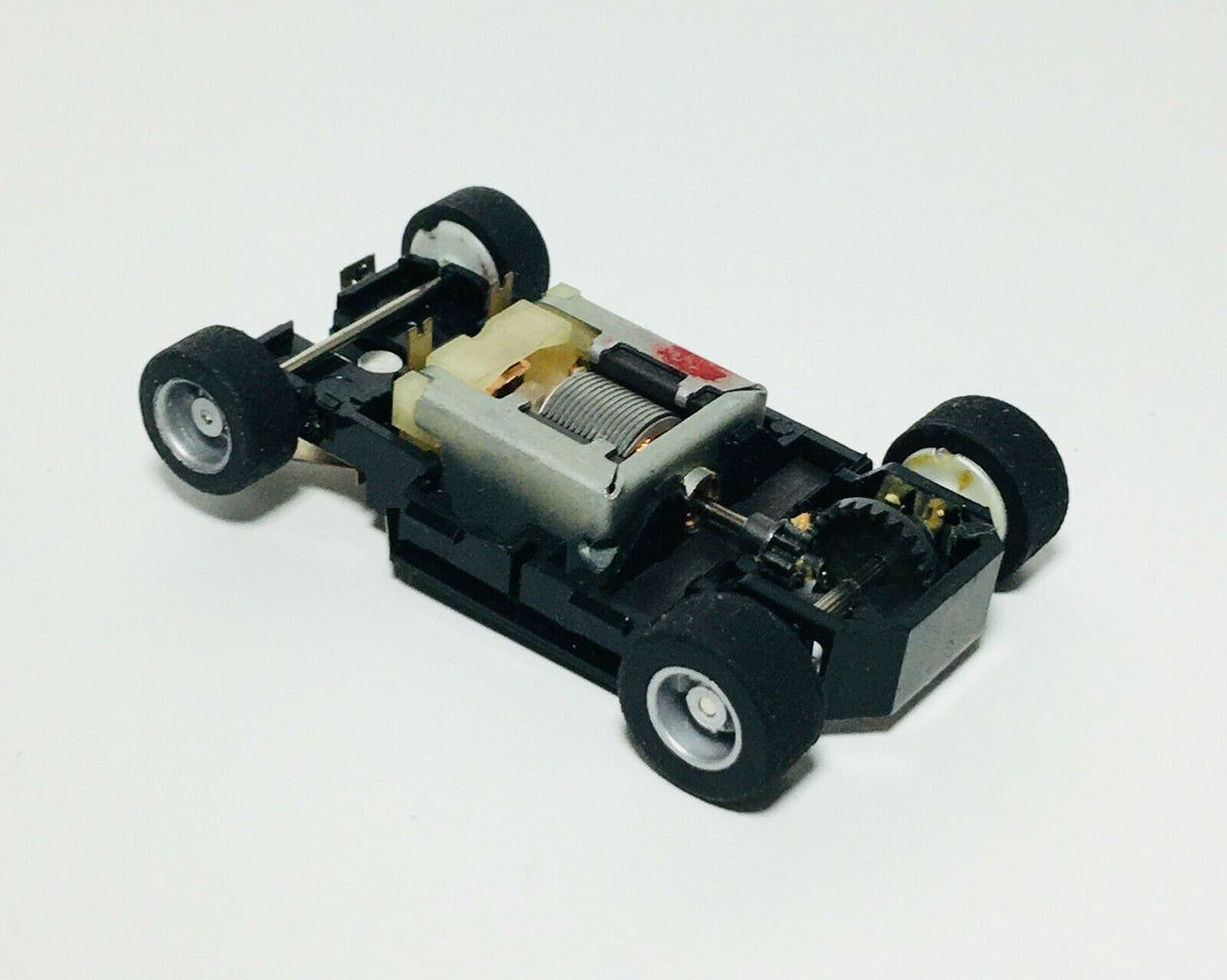 Small, black and silver electronic chassis with four wheels for Tyco