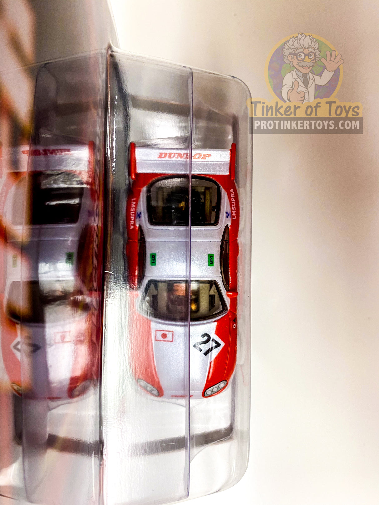 Two red toy cars displayed in a clear plastic case for Auto World SC346