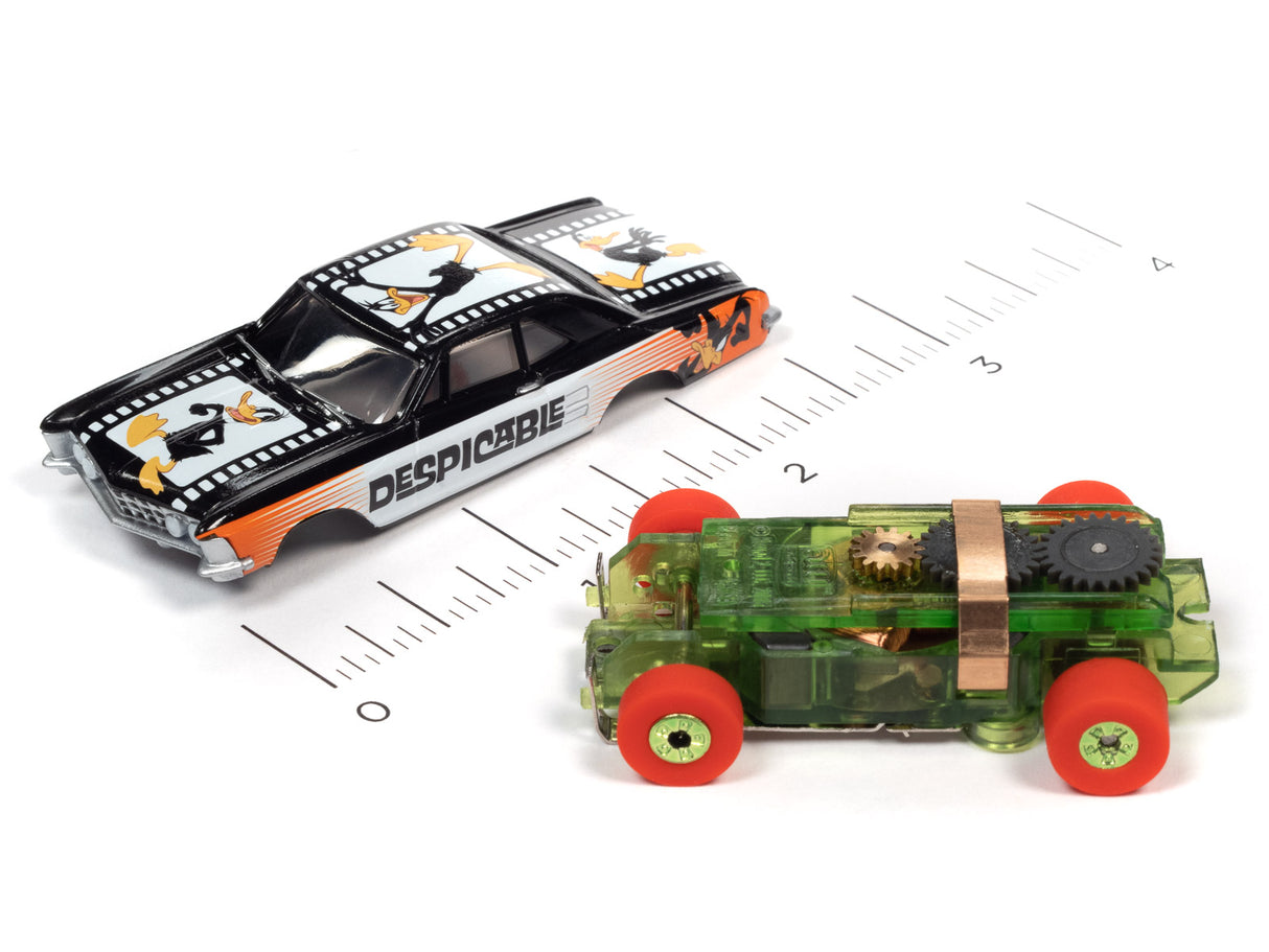 Two slot car toy cars: a black and orange "Despicable" car and a green, open-wheel car for Auto World SC363