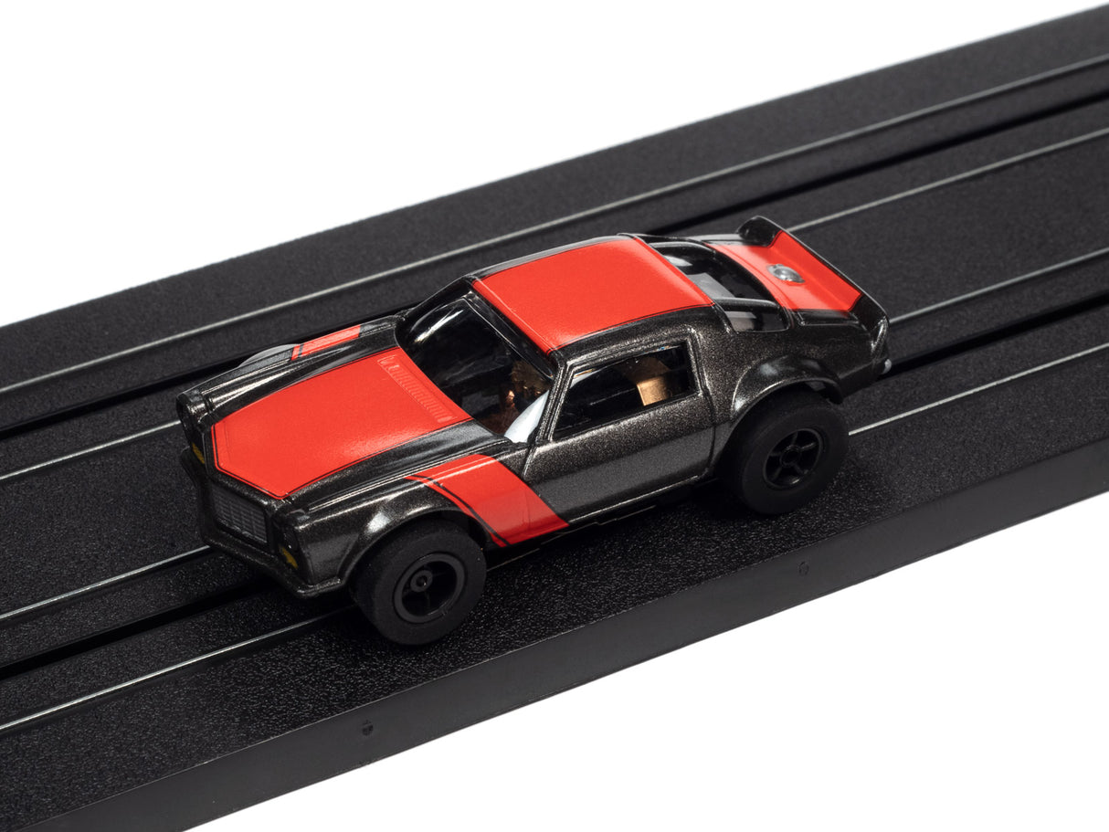 Red and black slot car on a black toy train track for Auto World SC366