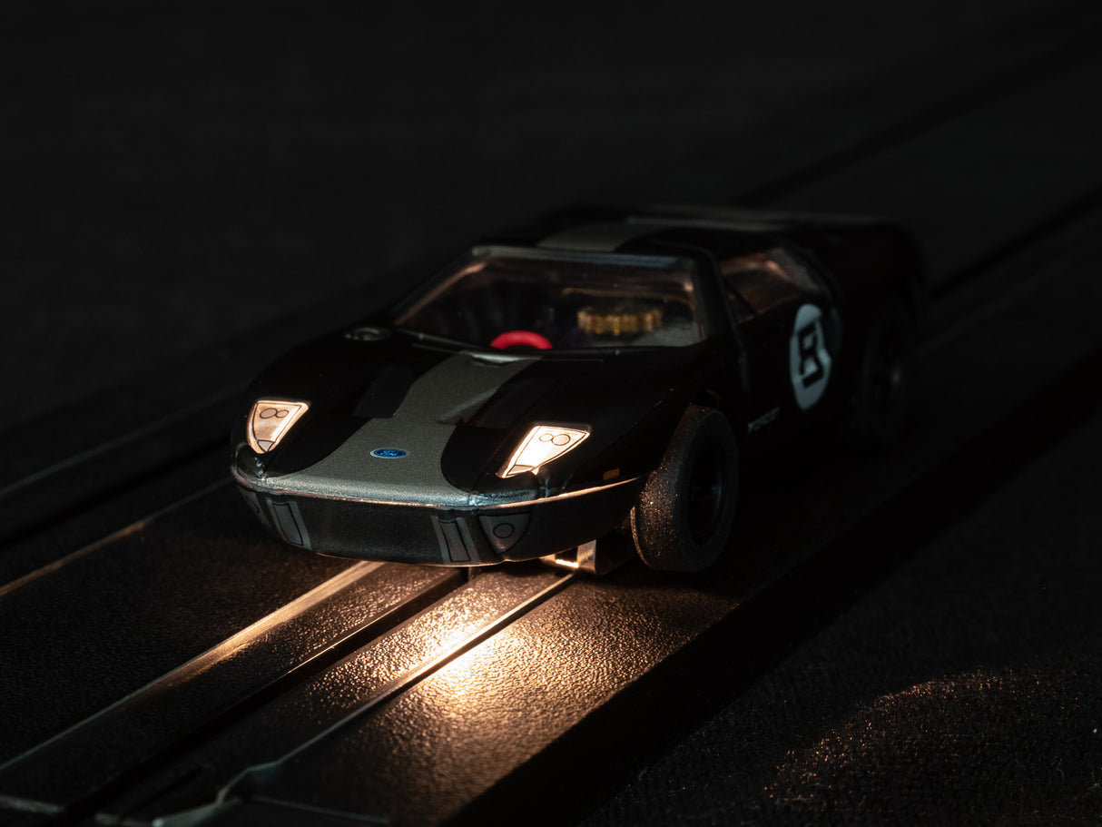 Black race car toy on track under dim, focused light for Auto World SC366