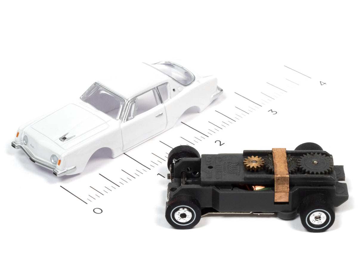 White car and black toy vehicle on a ruler scale for Auto World SC367