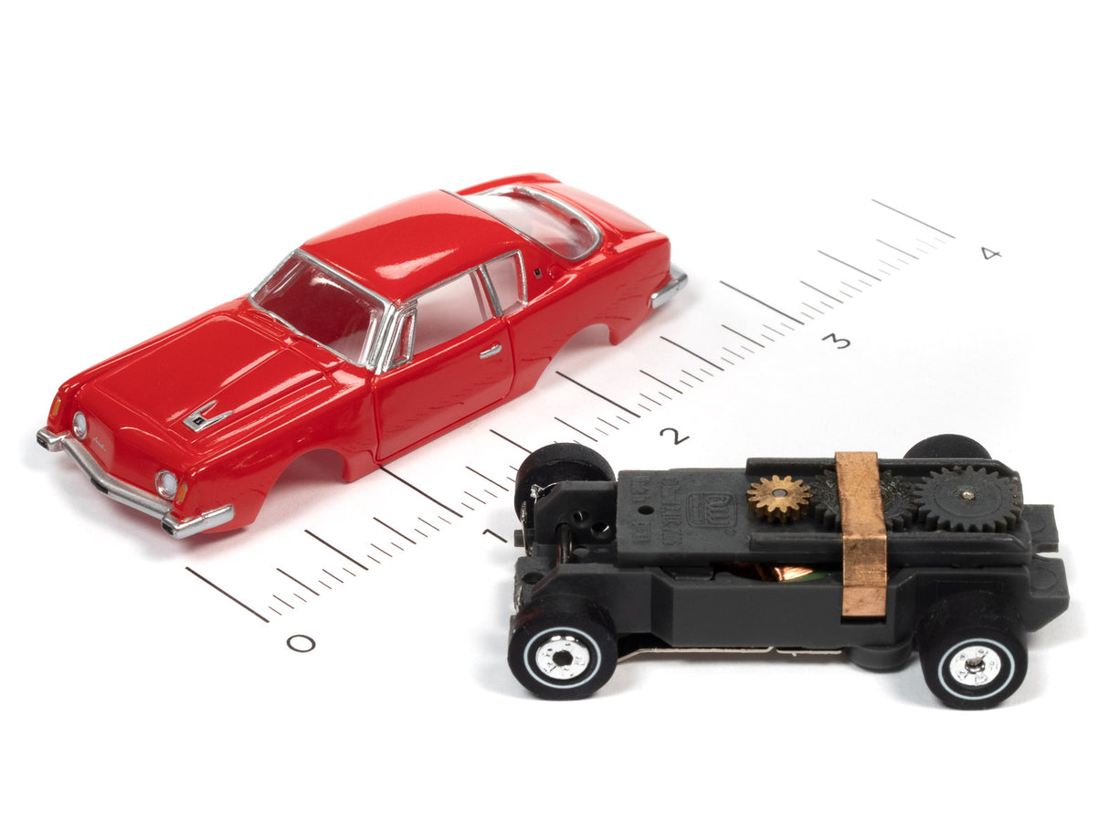 Red car and black toy vehicle on a ruler scale for Auto World SC367