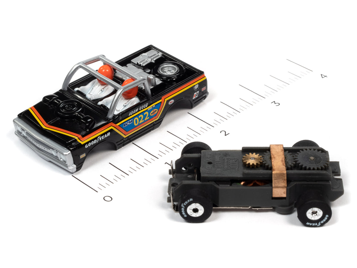 Two vintage toy cars, one black and yellow, one black, on a ruler for Auto World SC367
