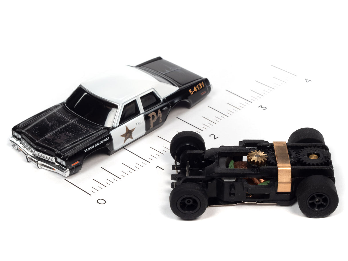 Black and white toy car and black toy vehicle on a ruler for Auto World SC372