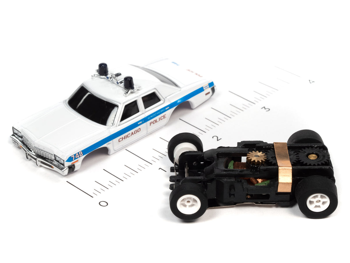 Toy police car and black toy car on a ruler for scale for Auto World SC372
