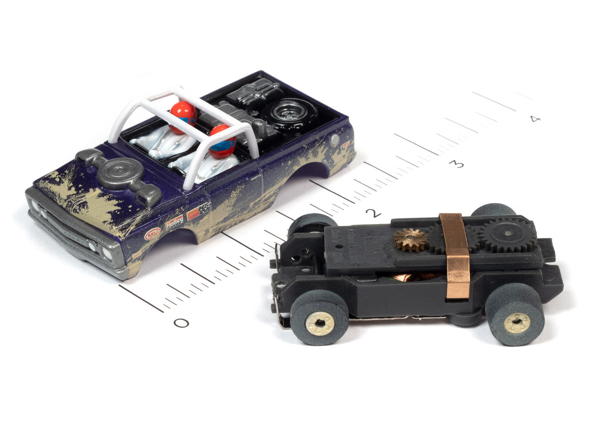 Two slot car off-road vehicles, one blue and one black, displayed on a ruler for Auto World SC375