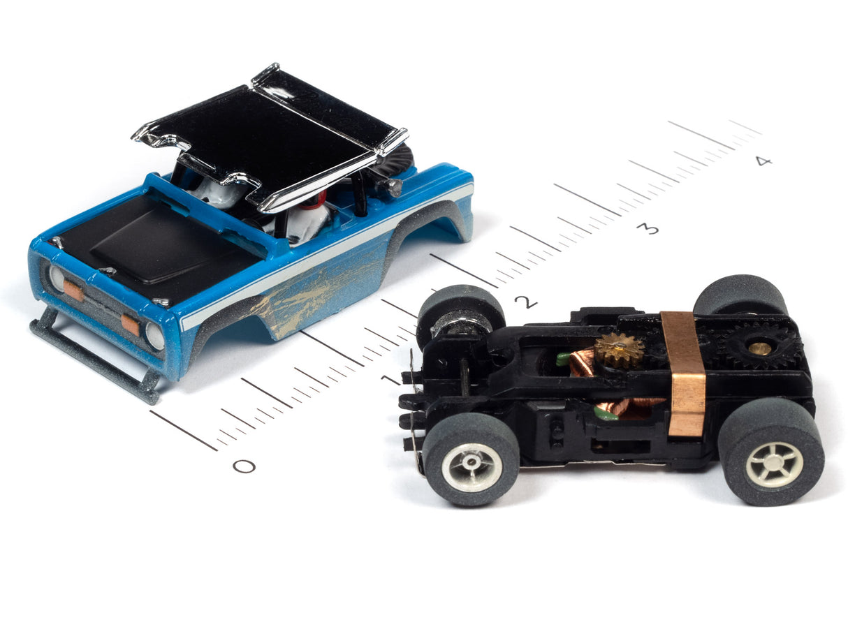 Two remote-controlled off-road cars displayed on a ruler for scale for Auto World SC375