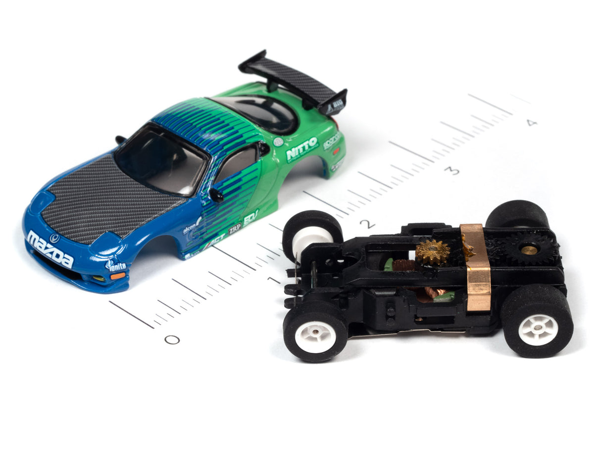 Blue and green slot car next to a black, disassembled car chassis for Auto World A SC378
