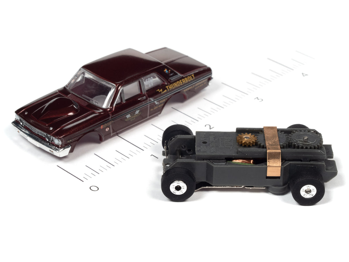 Two slot cars, a maroon sedan and a black vehicle, on a ruler for Auto World SC379