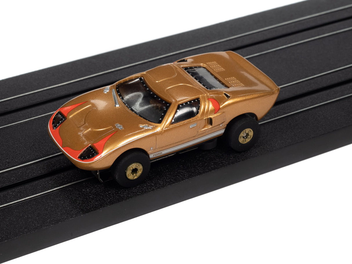 Gold Ford Thunderjet slot car on a black track for Auto World SC379