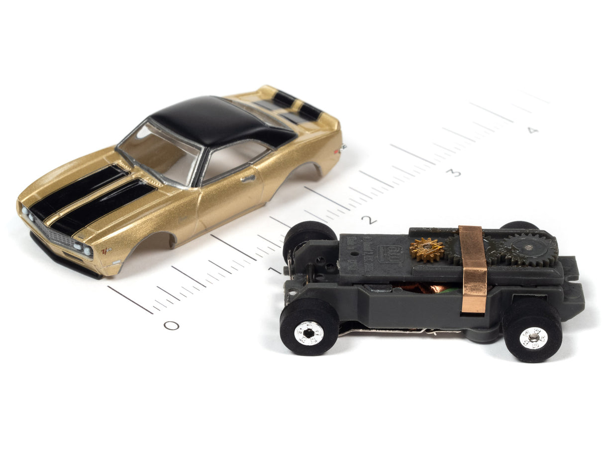 Gold and black slot cars on a ruler for scale comparison for Auto World SC379