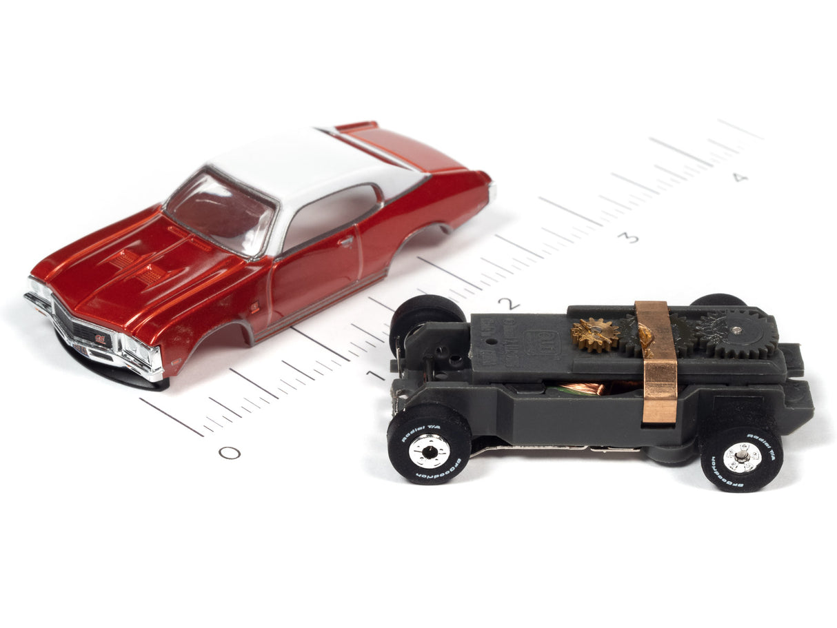 Red and white classic car next to a black, retro-style vehicle on a ruler for Auto World SC379