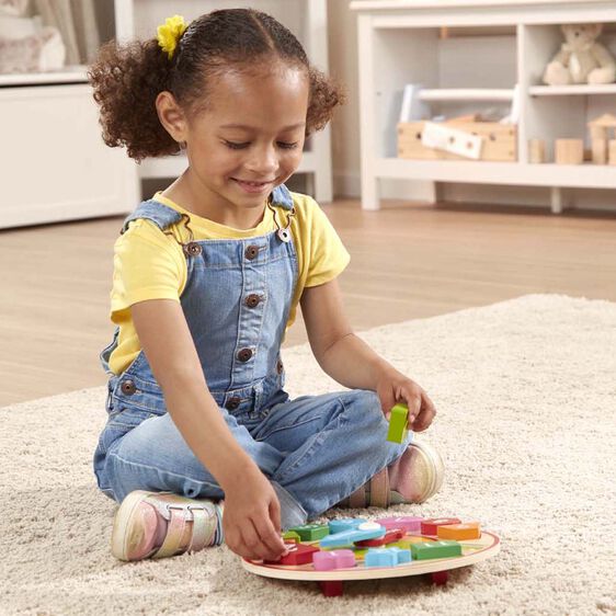 Girl sorts shapes on a clock toy, learning colors and numbers for Melissa and Doug 8593