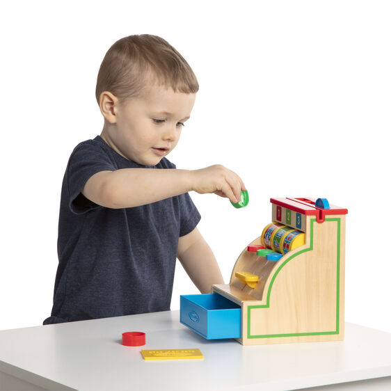 Toddler plays with a wooden cash register toy, simulating a shop experience for Melissa and Doug 3378