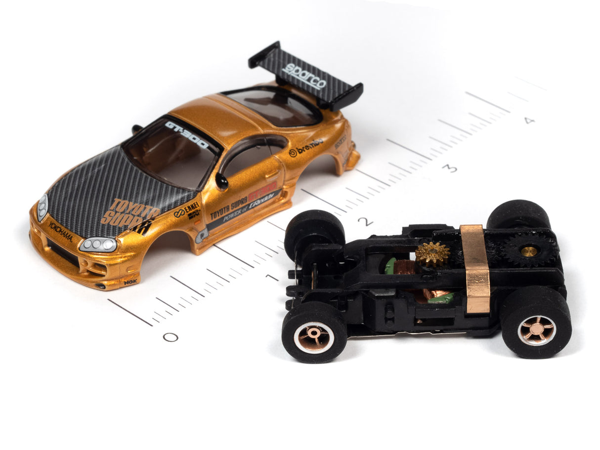 Gold and black slot car race cars on a ruler scale for Auto World SRS342