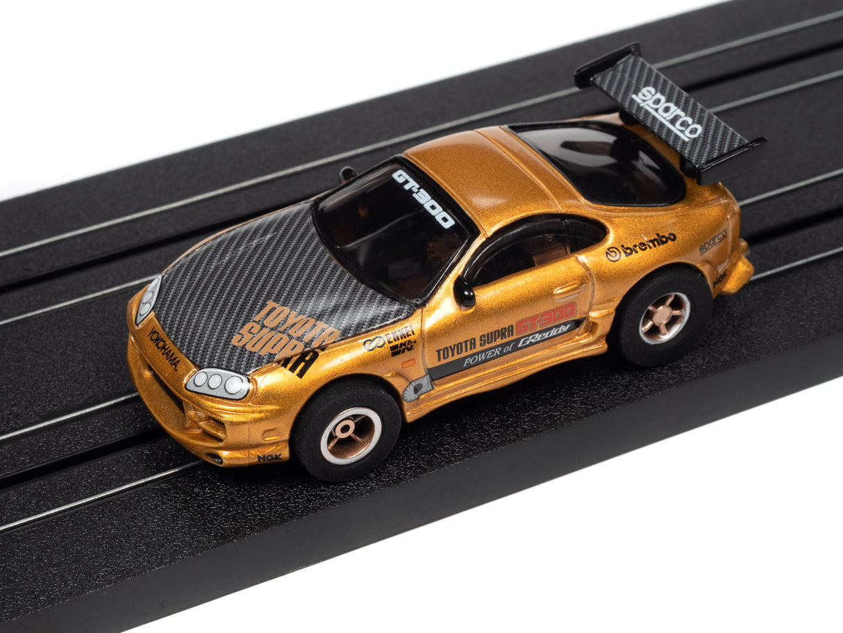 Gold Toyota Supra race car on a black slot track for Auto World SRS342