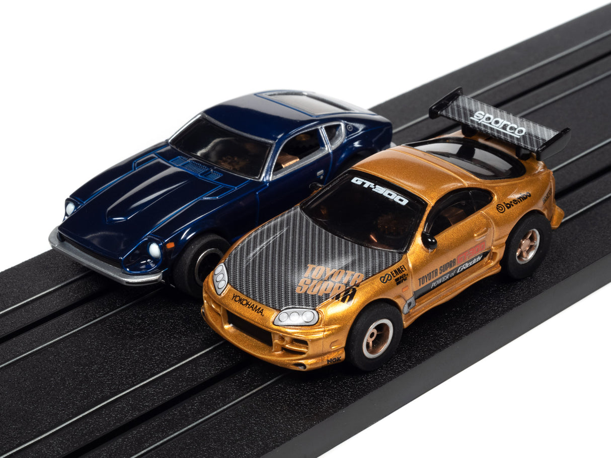 Two slot car race cars on a black slot car track for Auto World SRS342