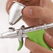 Spray gun nozzle attachment shown being held by hands for Grex Tritium.TG3