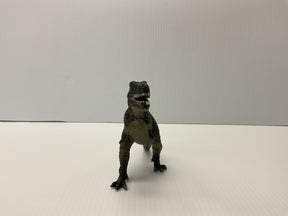 Small, dark T-Rex toy dinosaur standing on a white surface for Mamejo MAJ34005