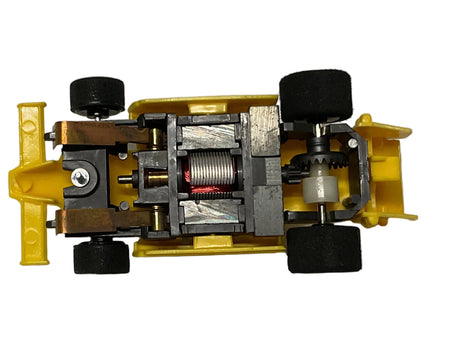 Yellow toy race car chassis with visible motor and wheels for Tyco B9100